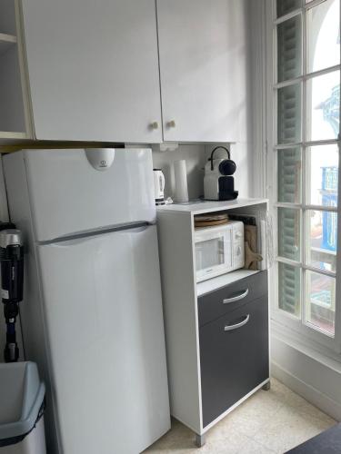 La cuisine est équipée d'un réfrigérateur blanc et d'un four micro-ondes. dans l'établissement La Falaise, à Mers-les-Bains