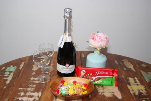 a bottle of wine and a bowl of candy on a table at Apartments Šlosarjeva Hiša Nature & Tradition in Preddvor
