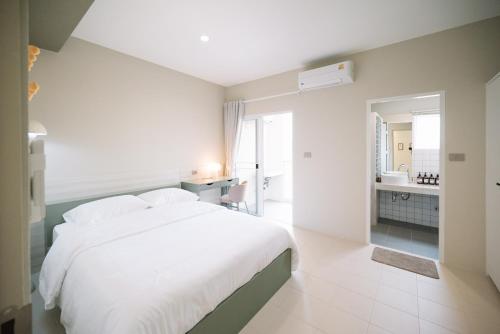 une chambre avec un lit blanc et une salle de bain dans l'établissement Slee สลี, à Chiang Rai