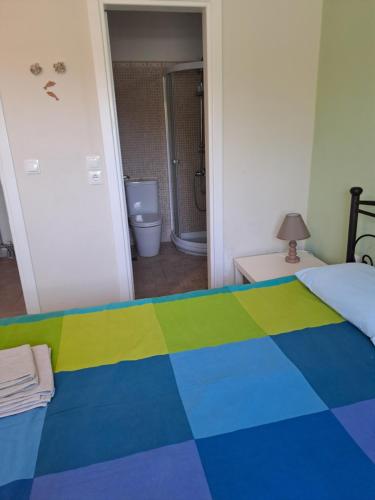a bedroom with a colorful bed with a bathroom at Sunset at Cape Sounio in Sounio