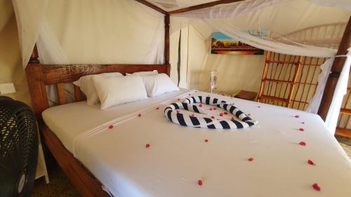 a bed with two pillows on it in a room at Kirepwe Ecco Camp Watamu in Watamu