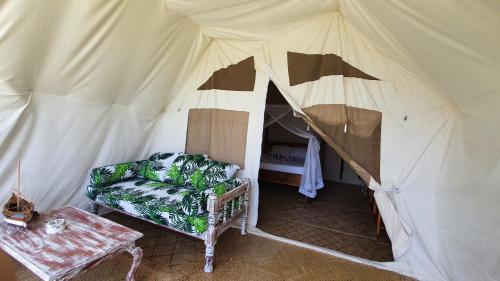 a tent with a couch and a table in it at Kirepwe Ecco Camp Watamu in Watamu