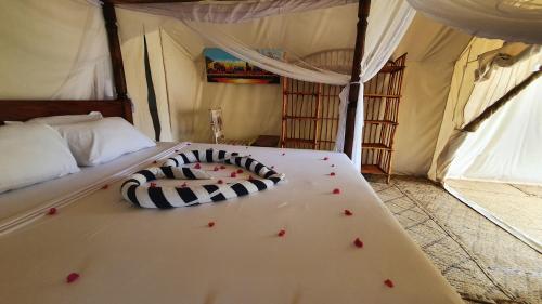 a bed in a tent with red flowers on it at Kirepwe Ecco Camp Watamu in Watamu