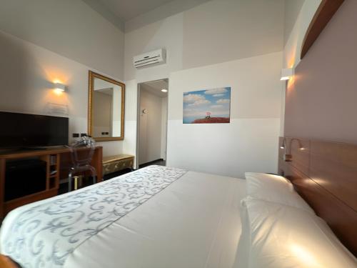 a bedroom with a white bed and a television at Hotel Europa Varese in Varese