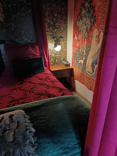 - une chambre avec un lit rouge et un tableau mural dans l'établissement La Pensine du célèbre sorcier, à Bourogne