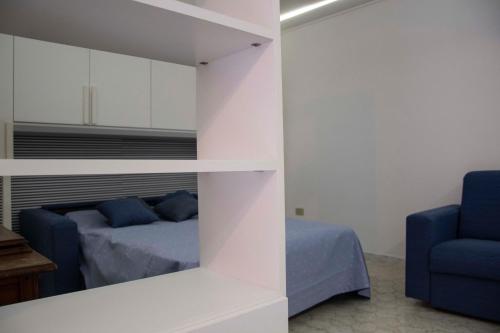 a bedroom with a bed and a mirror and a blue chair at Il Malazzeno, Monolocale in Pisciotta