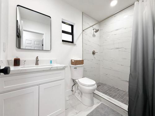 a white bathroom with a toilet and a shower at Modern Oasis near Brickell & Marlins 2 Bedroom Free parking in Miami