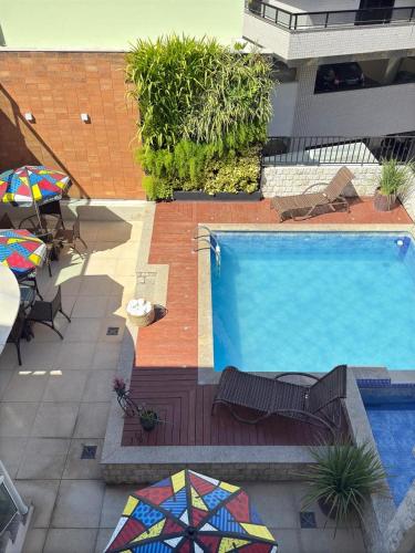 a swimming pool with a table and chairs and an umbrella at Pousada Mariá in Cabo Frio