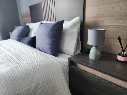 a bed with blue and white pillows and a table with a lamp at House of Bellavina in Fourways
