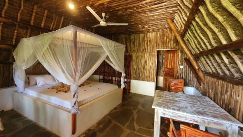 a bedroom with a bed with a mosquito net at Kirepwe Ecco Camp Watamu in Watamu