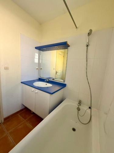 a bathroom with a tub and a sink and a mirror at Maison dans village vacances avec piscine in Gaujac