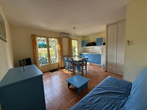 a living room with a bed and a table and a kitchen at Maison dans village vacances avec piscine in Gaujac