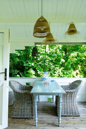 a table on a porch with wicker chairs at Huisje aan de Vijver in Hamme
