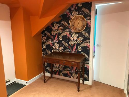 a clock on a wall next to a wooden table at Harbour view retreat with games room in Isle of Whithorn