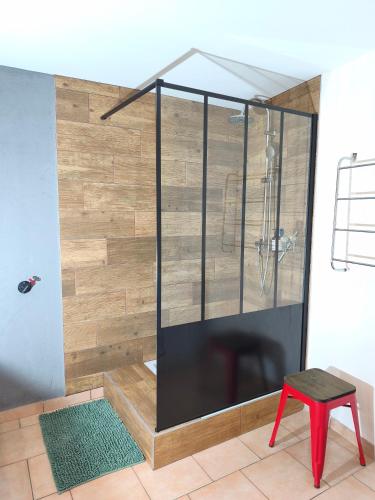 a shower stall in a room with a red stool at Gîte des trois petits oiseaux in Picarreau