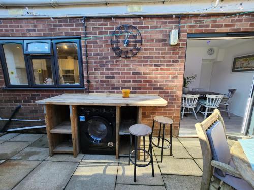 a patio with a table and stools in front of a brick wall at AnchorageWells Entire Cottage for 8 with 4 King Ensuite Rooms in Wells next the Sea