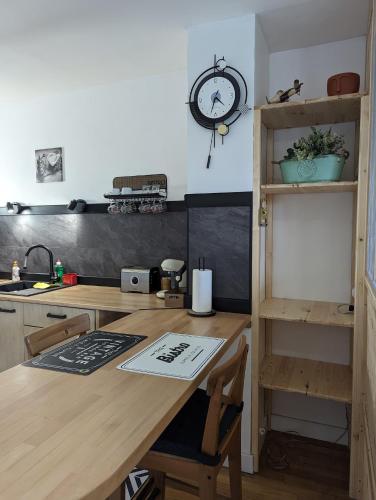 une cuisine avec une table en bois et une horloge au mur dans l'établissement Bayard la tour, à Charleville-Mézières