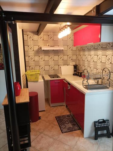 une cuisine avec des armoires rouges et un comptoir blanc dans l'établissement Gîte Rock - La Note Bleue, à Sainte-Radégonde-des-Noyers