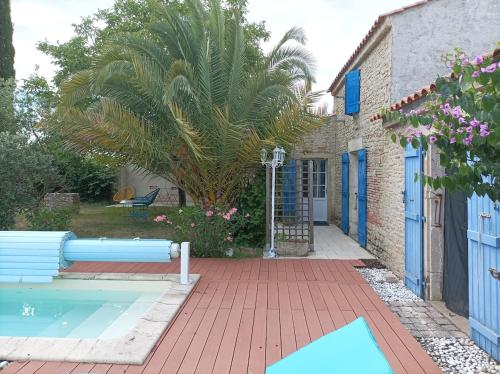 - une piscine à côté d'une maison avec un palmier dans l'établissement Gîte Rock - La Note Bleue, à Sainte-Radégonde-des-Noyers