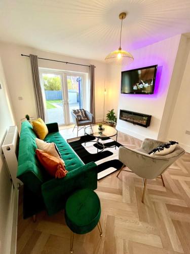 a living room with a green couch and a tv at Waterside House - Luxury Home near Alton Towers & Trentham - Free Parking & Garden in Stoke on Trent