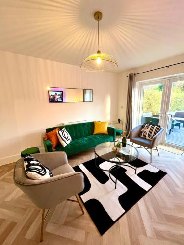 a living room with a green couch and a glass table at Waterside House - Luxury Home near Alton Towers & Trentham - Free Parking & Garden in Stoke on Trent
