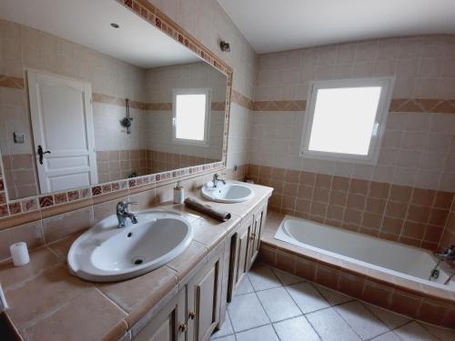 une salle de bain avec deux lavabos, une baignoire et un miroir dans l'établissement Somptueuse villa avec piscine chauffée, à Rousson