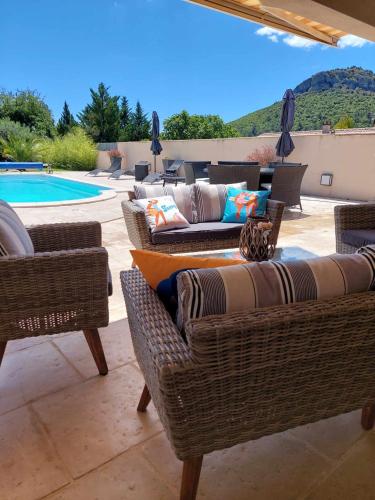 une terrasse avec mobilier en osier et une piscine dans l'établissement Somptueuse villa avec piscine chauffée, à Rousson