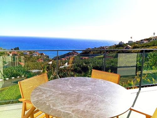 a table and chairs on a balcony with the ocean at Holiday House Caetano in Ponta do Sol