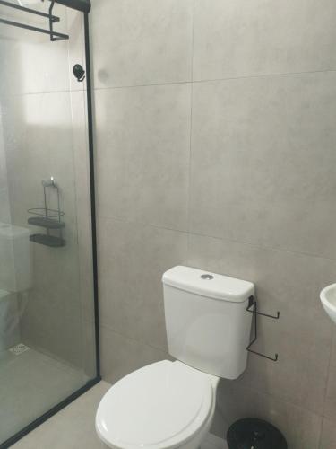 a bathroom with a toilet and a glass shower at Pousada da Vila Araçariguama-SP in Araçariguama