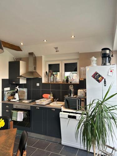 a kitchen with a white refrigerator and a table at LE GAI LO GITE in Villers-Pol