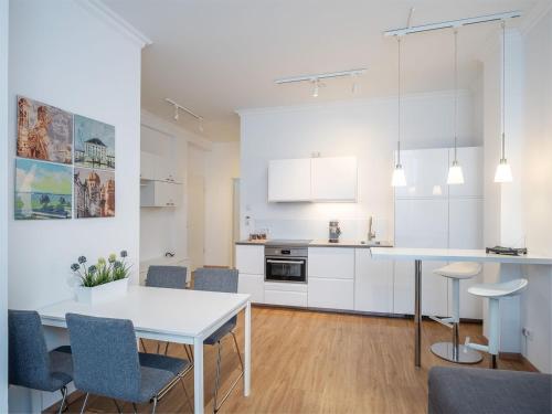 a white kitchen with a white table and chairs at Stylisch eingerichtete Wohnung mitten in München! in Munich