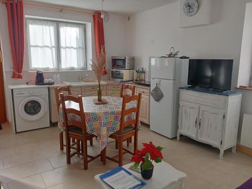 une cuisine avec une table, des chaises et un réfrigérateur dans l'établissement Maison avec jardin clos, proche du zoo de Beauval et des Châteaux de la Loire, à Meusnes