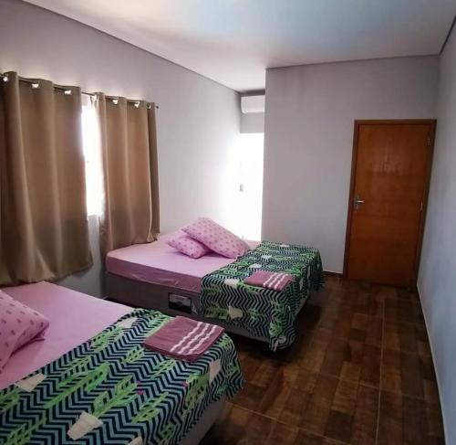 a room with two beds and a door with curtains at Canto dos Pássaros in Igarassú