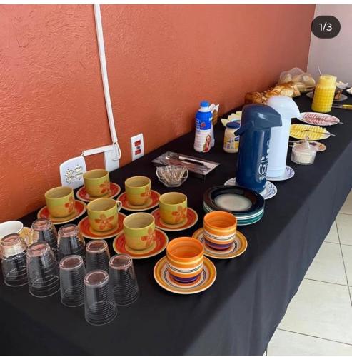 einem Tisch mit Teller, Tassen und Schüsseln in der Unterkunft Canto dos Pássaros in Igarassú