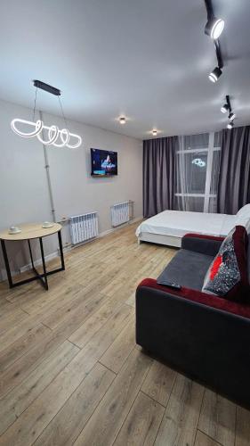 a bedroom with a bed and a table and a couch at 1 комнатные апартаменты in Semey
