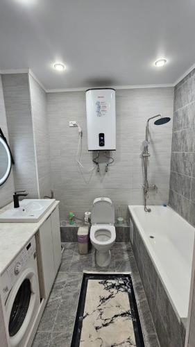a bathroom with a toilet and a washing machine at 1 комнатные апартаменты in Semey