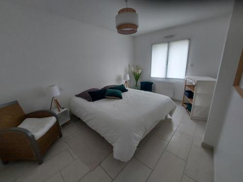 une chambre blanche avec un lit et une chaise dans l'établissement Ty Nez, Séjour Cosy, à Riec-sur-Bélon