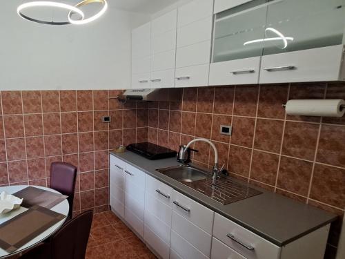 a kitchen with white cabinets and a sink and a table at NADJA apartmani in Šabac