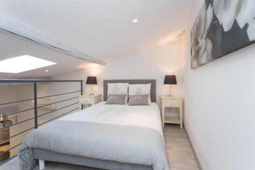 a bedroom with a white bed and two tables at Grand studio République in L'Isle-sur-la-Sorgue