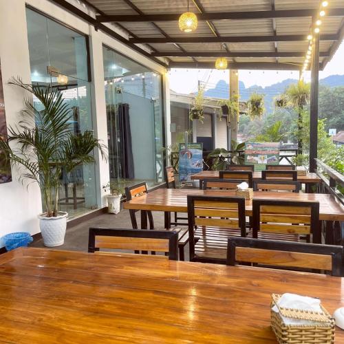 a restaurant with wooden tables and chairs and windows at Smile Guesthouse VangVieng in Vang Vieng