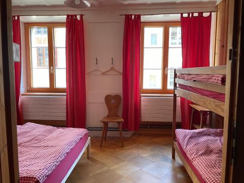 a room with two bunk beds and red curtains at Maison La Coquille in La Chaux-de-Fonds