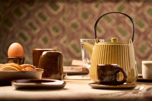 a table with a tea kettle and eggs on it at Hostellerie Du Chapeau Rouge in Dijon