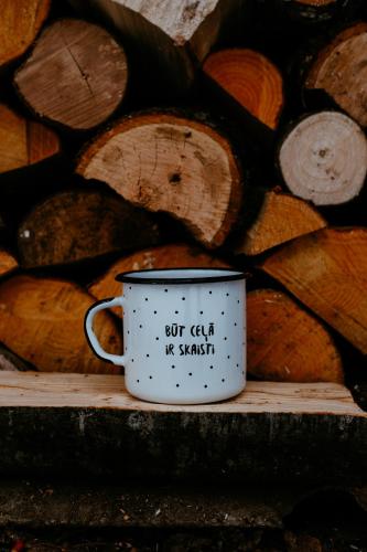 a coffee cup sitting on a table next to a pile of logs at Koka namiņš "Pasaka" in Vecumnieki