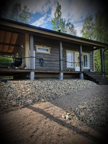 a small cabin with a porch on a rocky yard at Uiton kotirantasauna in Kiemunkivaara