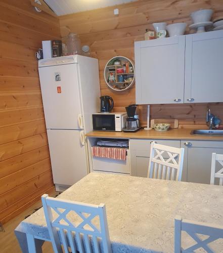 a kitchen with a refrigerator and a table and chairs at Uiton kotirantasauna in Kiemunkivaara