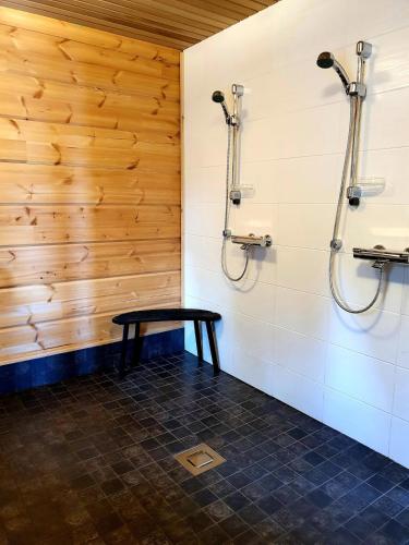a bathroom with two shower stalls and a bench at Uiton kotirantasauna in Kiemunkivaara