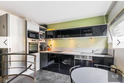 une cuisine avec des armoires en noir et blanc et une table dans l'établissement Triplex cosy, à Lyon