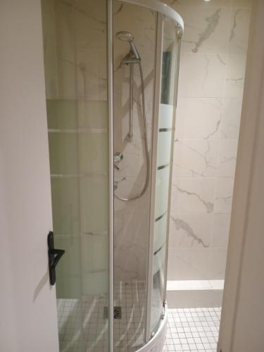 une douche avec une porte vitrée dans une salle de bain dans l'établissement 2 pièces proche centre villes, à Paris