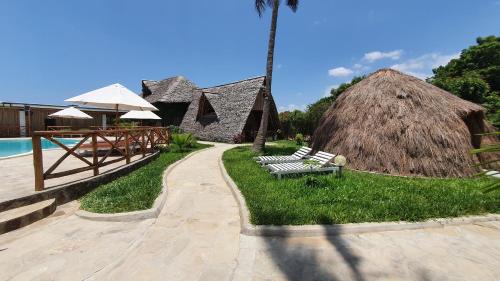 a resort with a bench and a thatch roof at Kirepwe Ecco Camp Watamu in Watamu