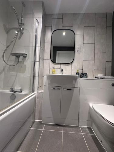 a bathroom with a sink and a tub and a mirror at Cosy Flat in Stevenage Town Centre in Stevenage